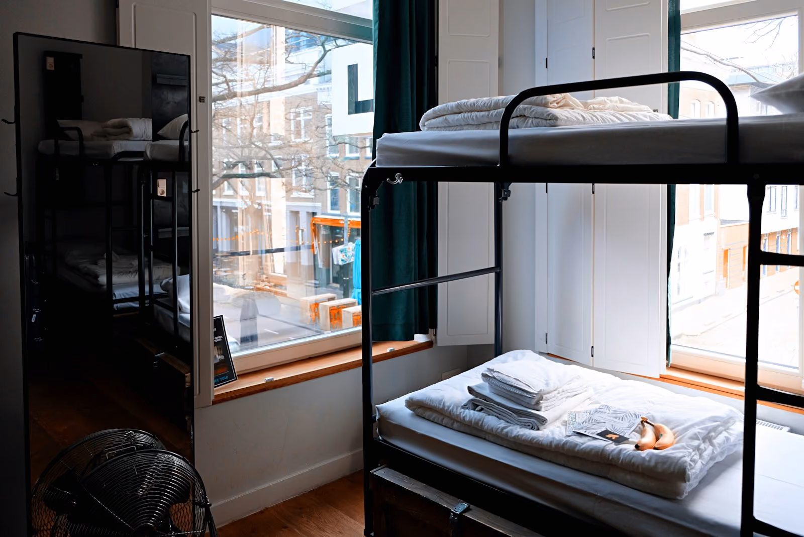 A dormitory room with bunk beds dressed in white linens